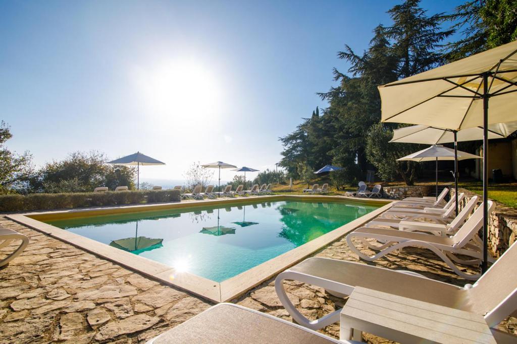 - une piscine avec des chaises longues et un parasol dans l'établissement Villa Godenano - Country Chianti Villa, à Castellina in Chianti