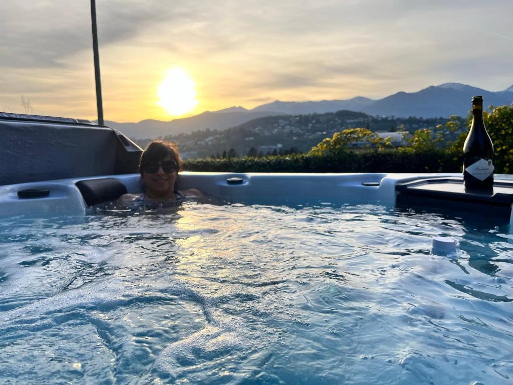 Una donna in una vasca idromassaggio con una bottiglia di vino di Villa Vanessa SUITES a Lugano
