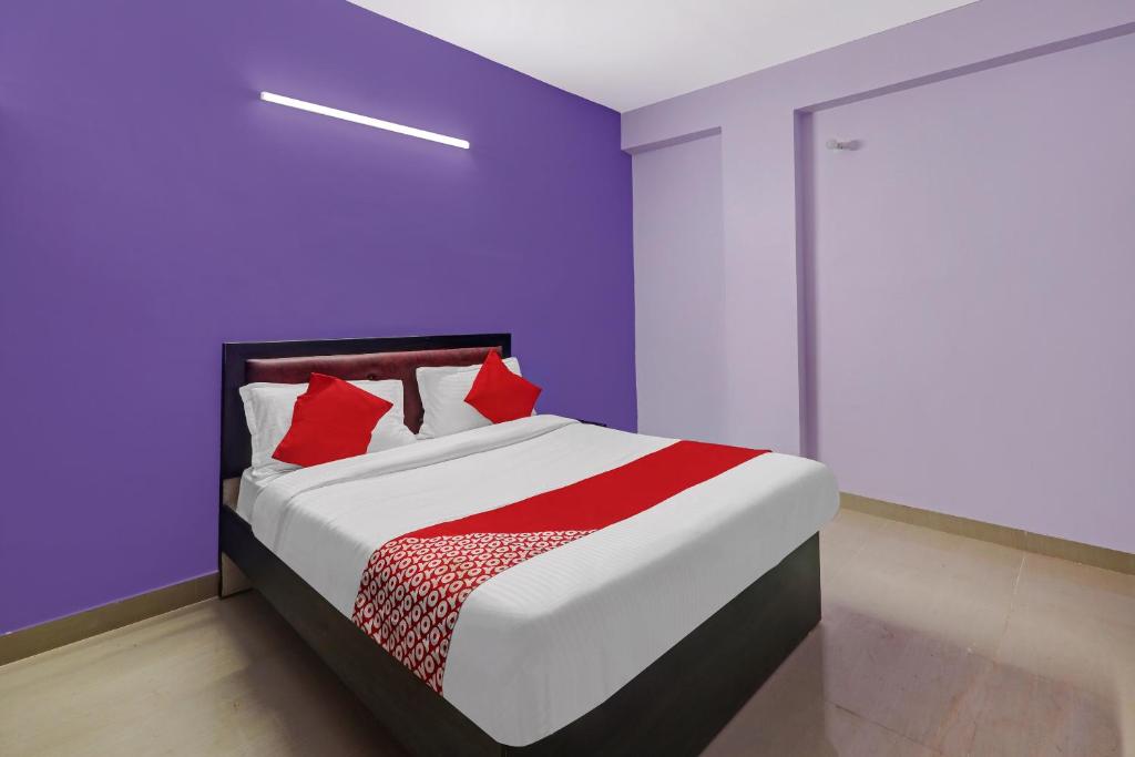 1 dormitorio con 1 cama con paredes moradas y almohadas rojas en OYO Flagship 24 Stays, en Chinhat