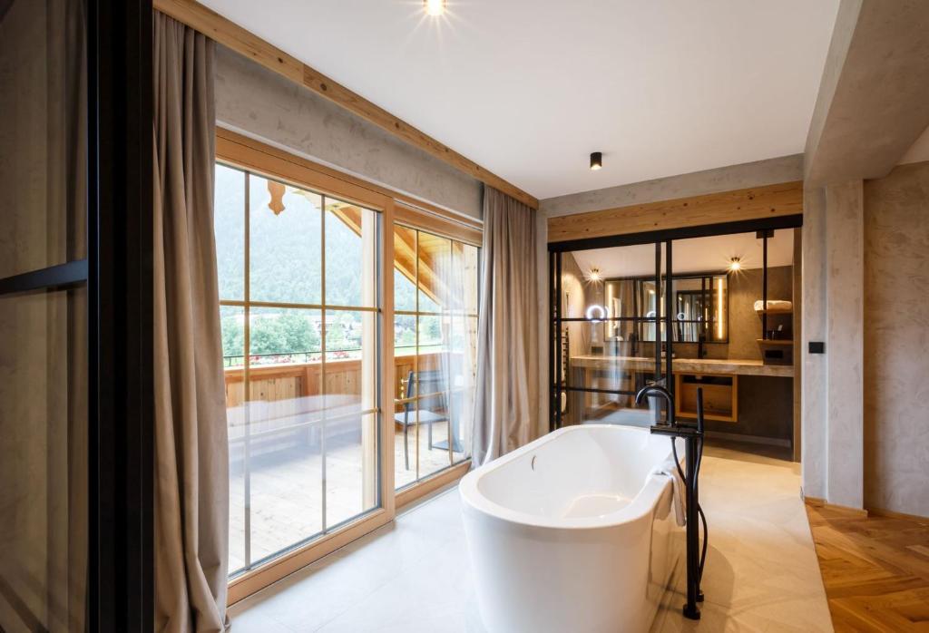 Una bañera en un baño con una ventana grande. en NOVA Moments Boutique Hotel, en Pertisau