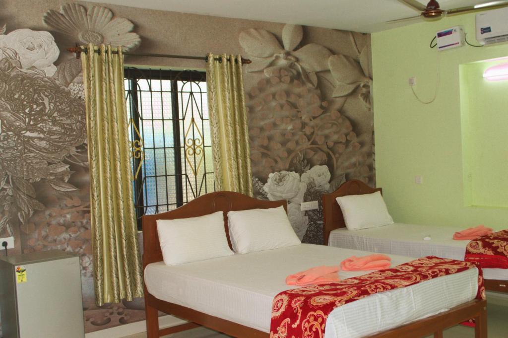 een slaapkamer met 2 bedden en een muur met bloemen bij Flavia Paradise Guest House in Canacona