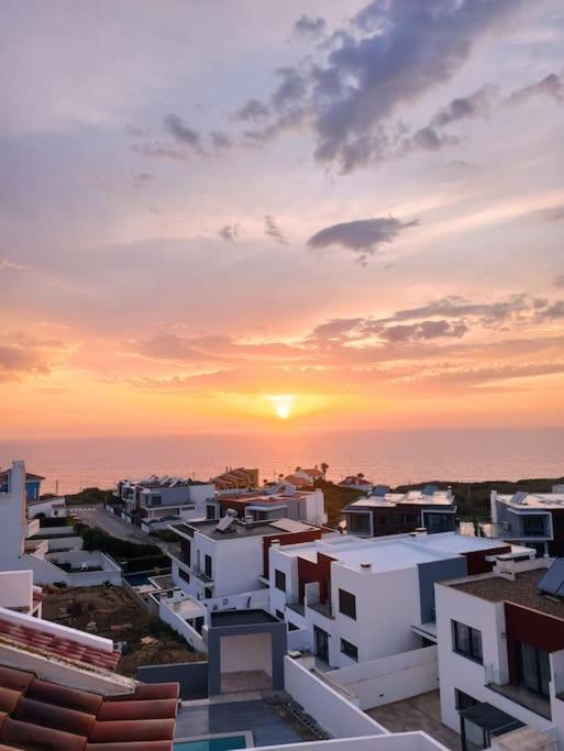 un tramonto su una città con edifici bianchi e l'oceano di Merci Beach House a Carvoeira