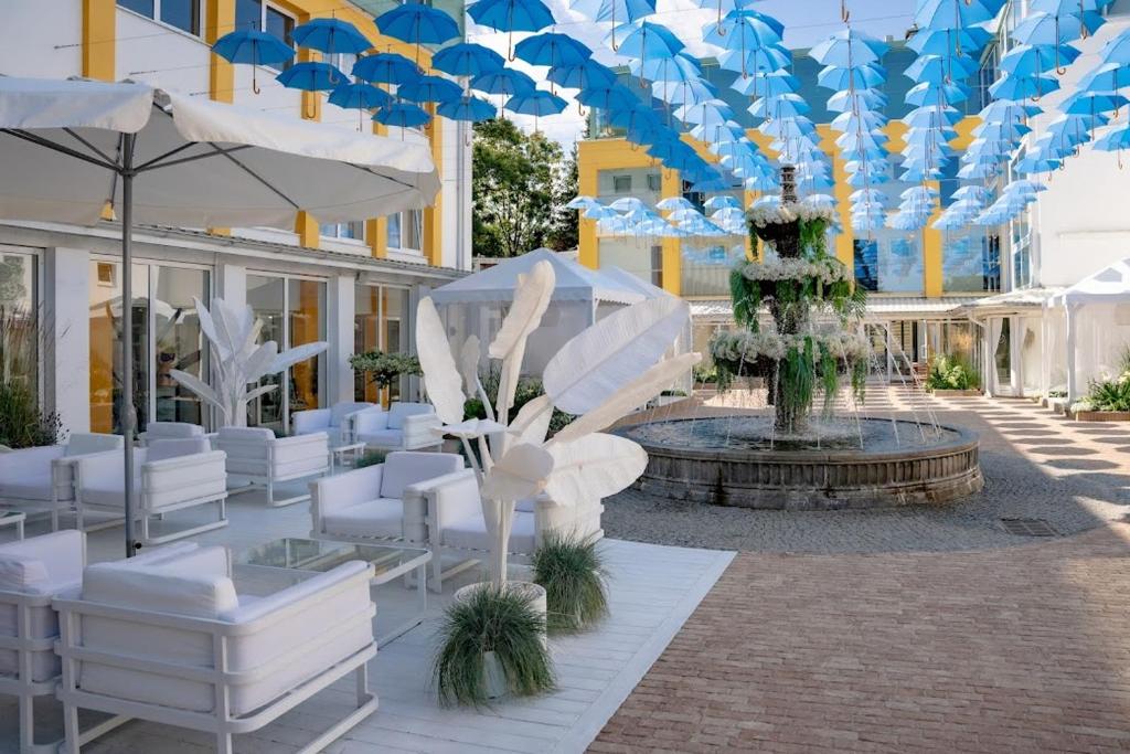 a courtyard with white chairs and a fountain with umbrellas at Hotel Bryza Resort & Spa in Jurata