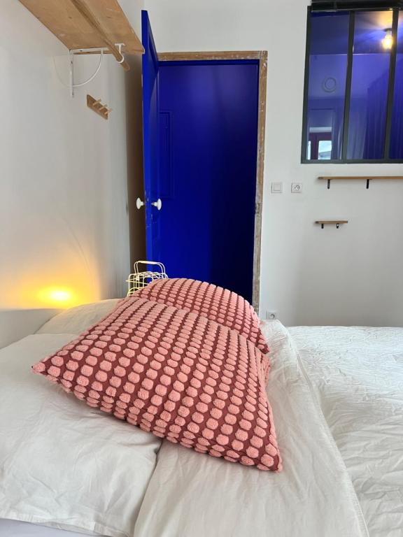 a bed with a pink pillow sitting on top of it at Chambre proche Stade de France, métro à 5min in Saint-Denis