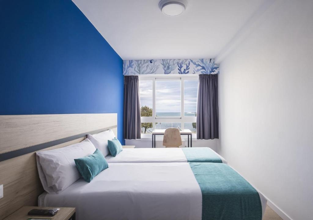 ア・コルーニャにあるAlda Coruñamarのベッド2台と窓が備わるホテルルームです。