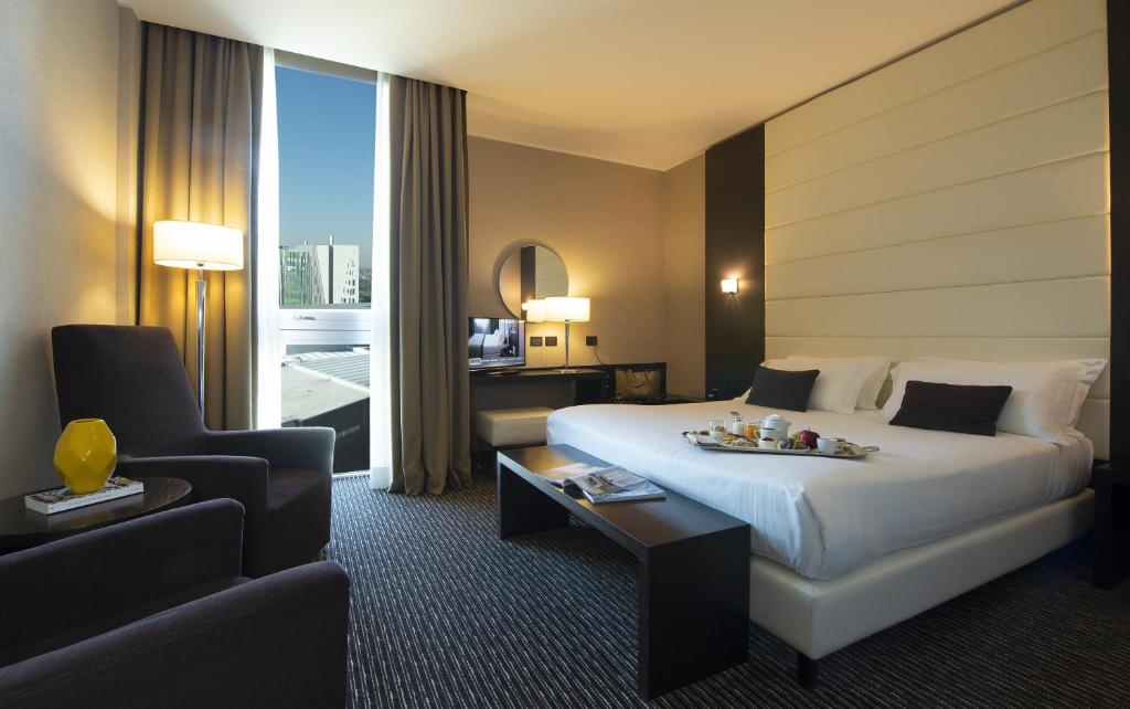 una habitación de hotel con una cama grande y una silla en H2C Hotel Milanofiori, en Assago