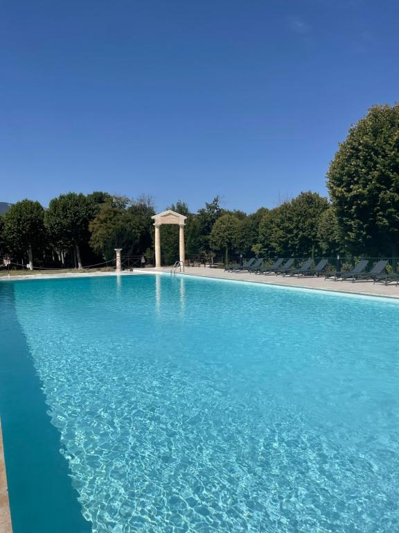 una piscina de agua azul con un monumento en el fondo en le 24 du château en Montbrun-les-Bains