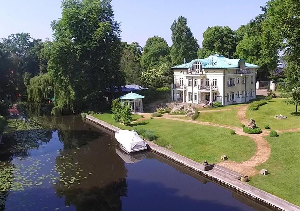 une grande maison avec un bateau sur une rivière dans l'établissement FeWo Havelpalais direkt am Wasser, à Potsdam