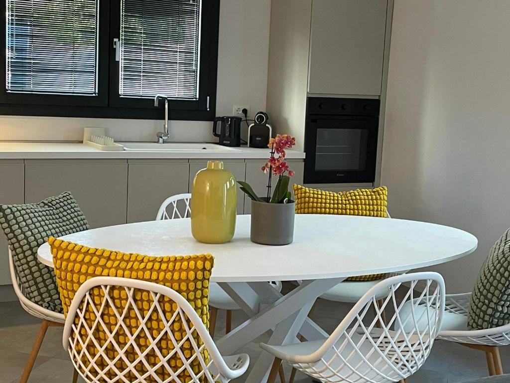 una mesa blanca con sillas y un jarrón amarillo. en Elisa Apartments A - in front of the walls of Lucca, en Lucca