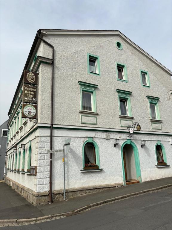 a white building with green windows on a street at Goldener Loewe in Wunsiedel