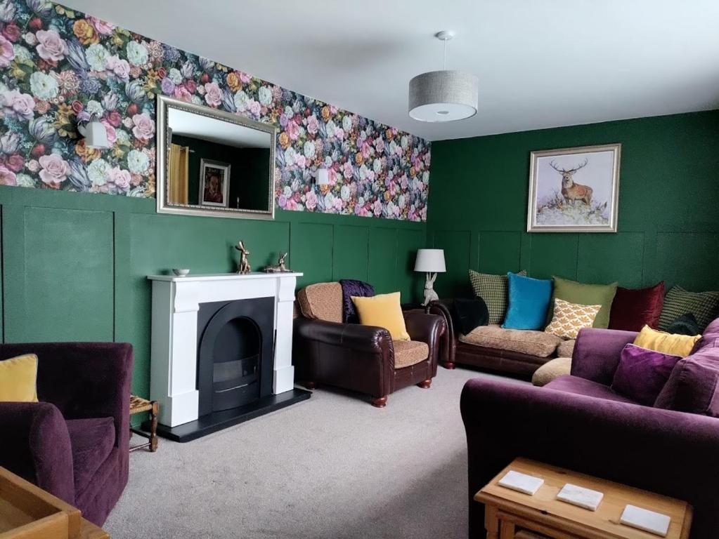 a living room with green walls with couches and a fireplace at Woldsend in Moreton in Marsh