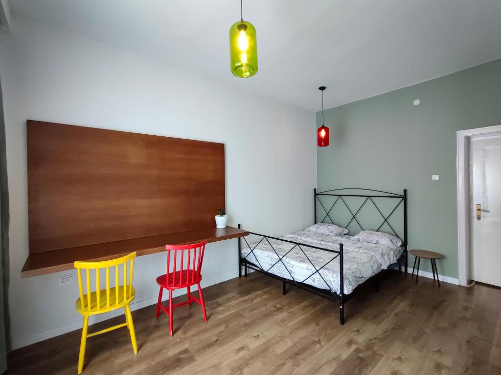 1 dormitorio con 2 sillas, 1 cama y escritorio en Hostel Charming Double Private Room, en Pristina