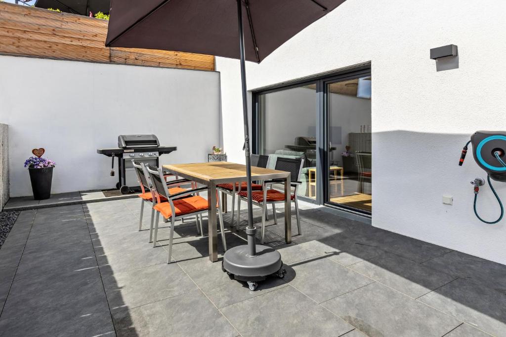 een patio met een tafel en stoelen en een grill bij Stegmann Horn in Gaienhofen