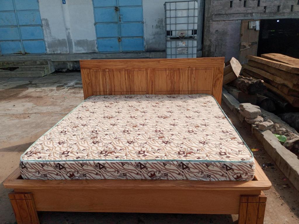 een houten bed in een verlaten kamer bij Matelas PEB in Cotonou