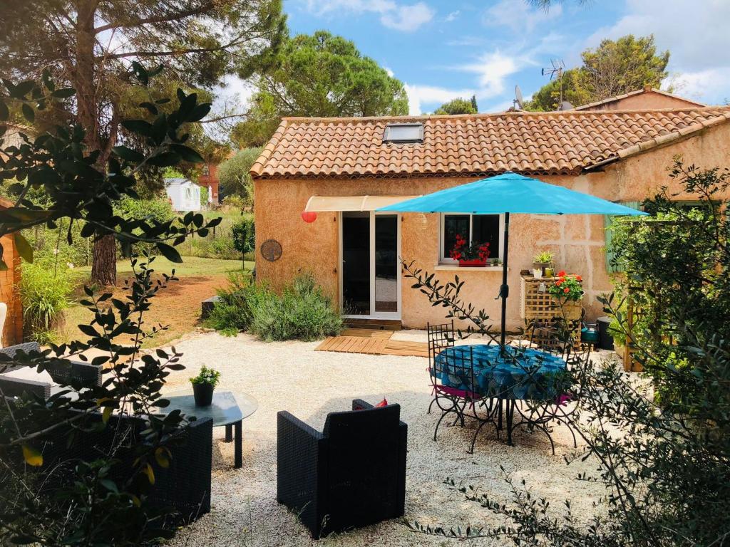 une terrasse avec une table et un parasol bleu dans l'établissement les crins de la renardière, à Villeveyrac