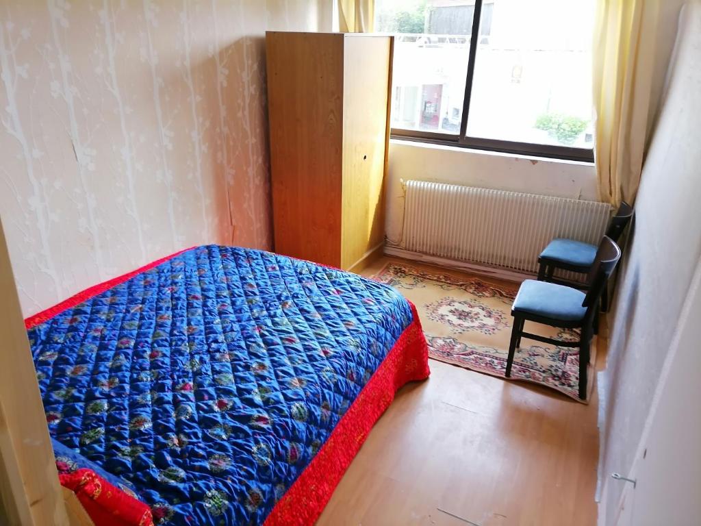 1 dormitorio con cama, ventana y silla en Hôtel familial de Saint-Georges, en Villeneuve-Saint-Georges