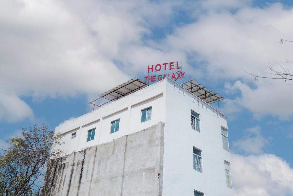 Hotel The Galaxy في Dabok: علامة الفندق فوق مبنى ابيض