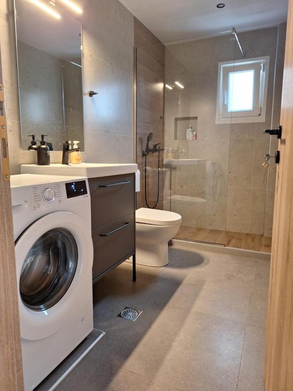 y baño con lavadora y aseo. en modern apt near Heraklion city & airport, en Néa Alikarnassós