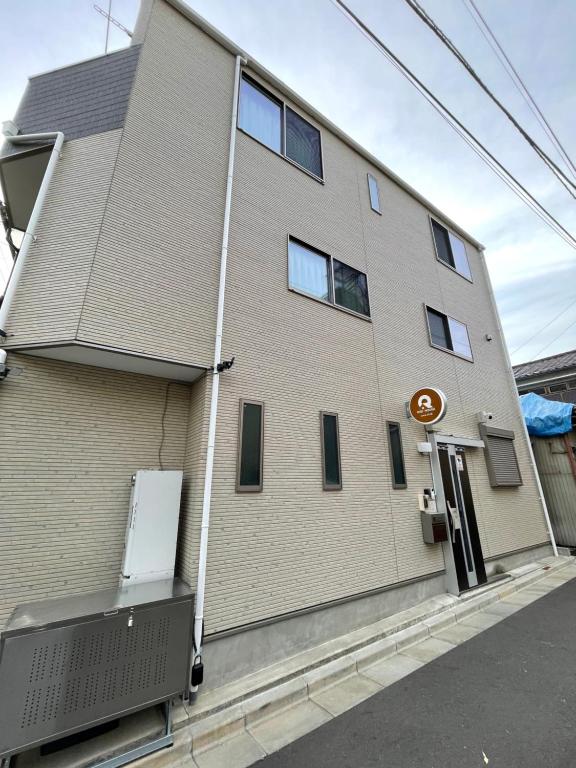 a brick building with a sign on the side of it at QiQi House Serenity 新築一軒家宿 Brand New Exclusive 3-Story House Near Tokyo Skytree Asakusa in Tokyo