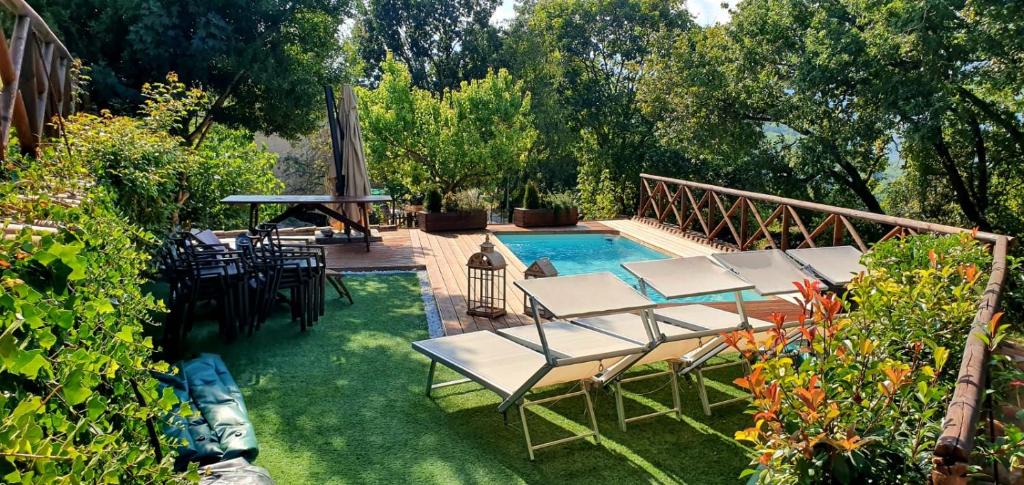 a swimming pool with chairs and a table next to a yard at La Dimora dei Baldi - Rooms & Relax in Fagnano Alto