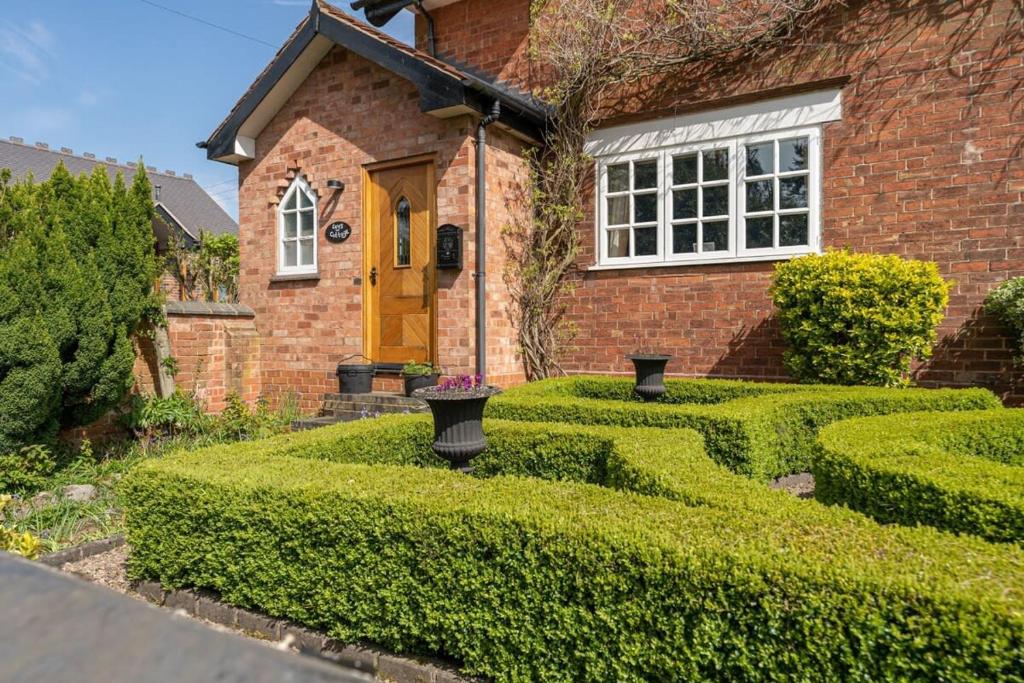 a brick house with hedges in front of it at Beautiful country cottage for 8 - great staycation in Wolverhampton