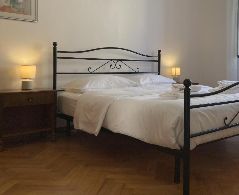 um quarto com uma cama grande com lençóis brancos e almofadas em Gli Acquerelli em Trieste