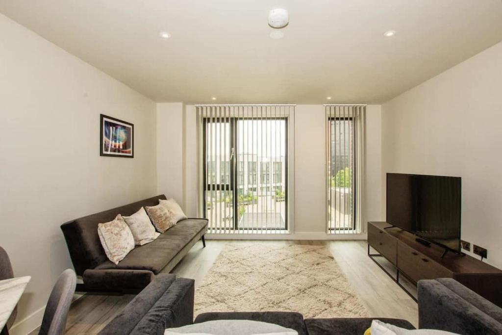 a living room with a couch and a flat screen tv at St Martin's Place Apartment - Bham City Centre in Birmingham