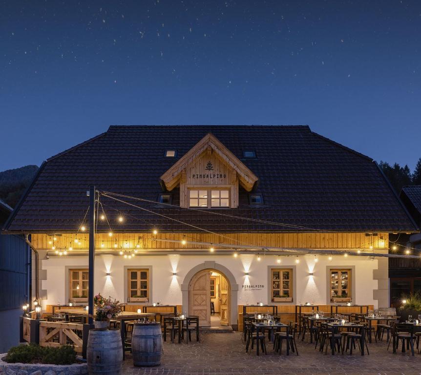 a large white building with tables and chairs at night at Hotel Pino Alpino in Kranjska Gora