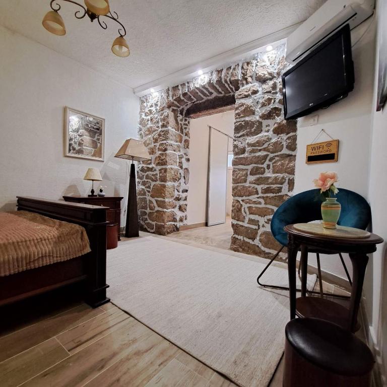 a bedroom with a stone wall with a bed and a television at Unique Apartment Centar in Podgorica