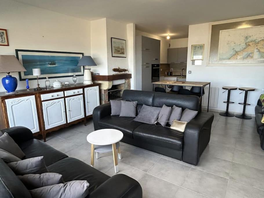 uma sala de estar com um sofá preto e uma cozinha em Appartement sur la plage em Pléneuf-Val-André