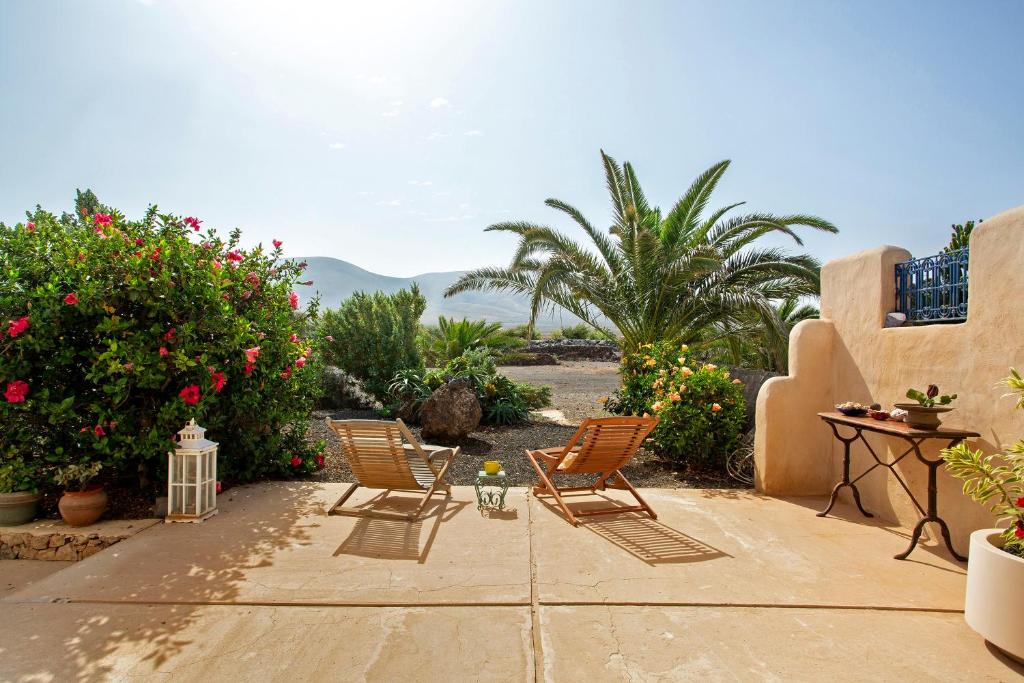 a patio with two chairs and some plants and flowers at La Agüita in playa del Águila