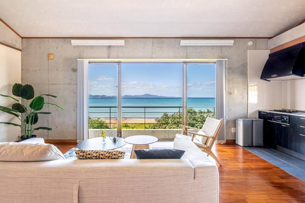 a living room with a couch and a large window at ヴィラ カエルラ in Nago