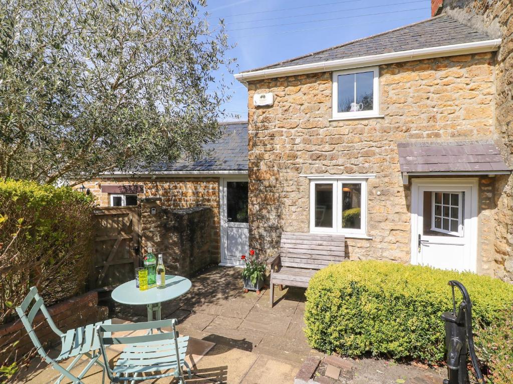 une maison en pierre avec une table et des chaises devant elle dans l'établissement Tiddlers Cottage, à Bridport