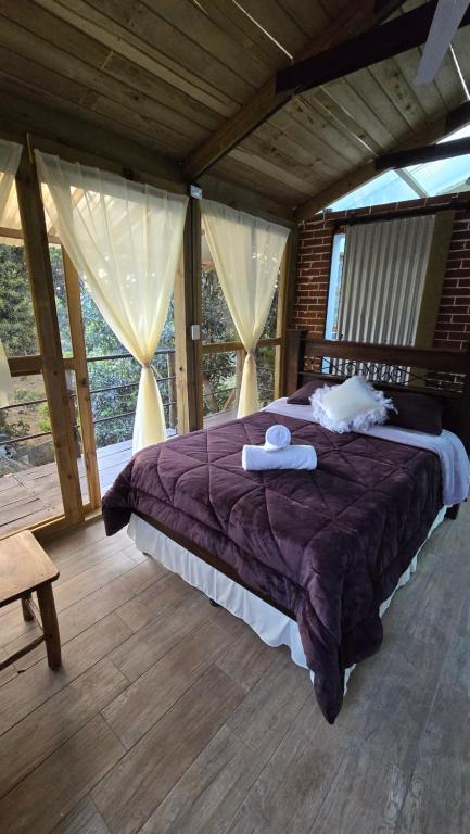 a bedroom with a large bed in a room with windows at Cabaña Cristal 