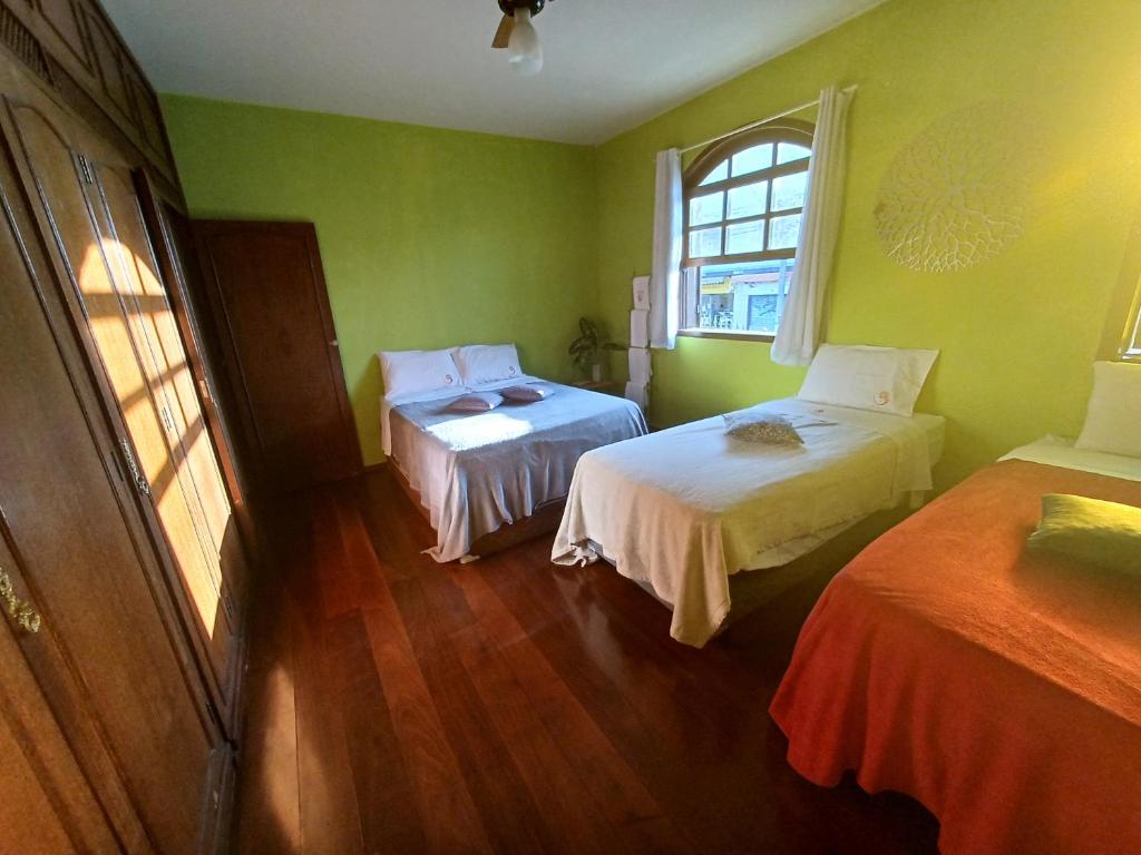 a green room with two beds and a window at Naturaleza - Pousada & Centro Holístico in Lavras