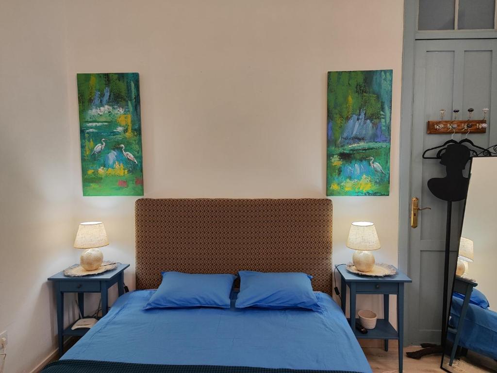 um quarto com uma cama com lençóis azuis e pinturas em Charming studio in Tazacorte em Tazacorte