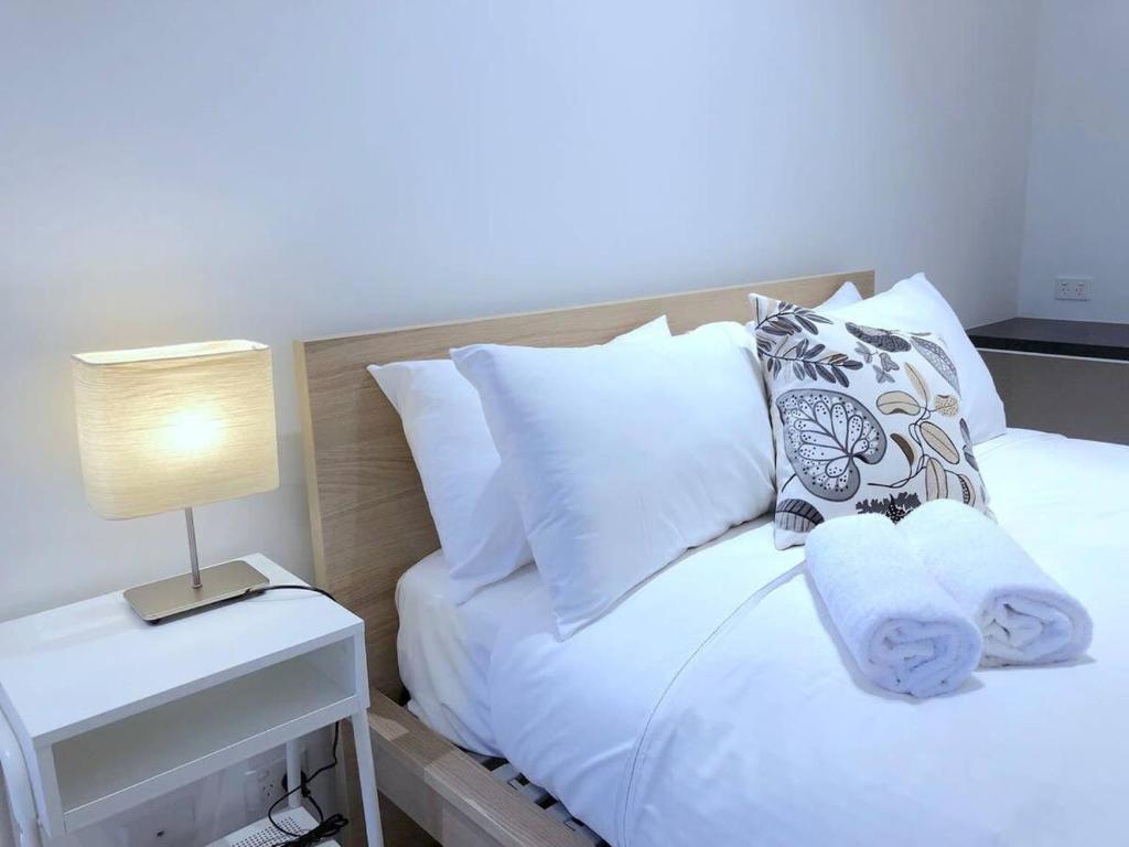 メルボルンにあるFawkner Residence 1B2B condo Smart TVのベッド(白い枕、テーブルの上のランプ付)