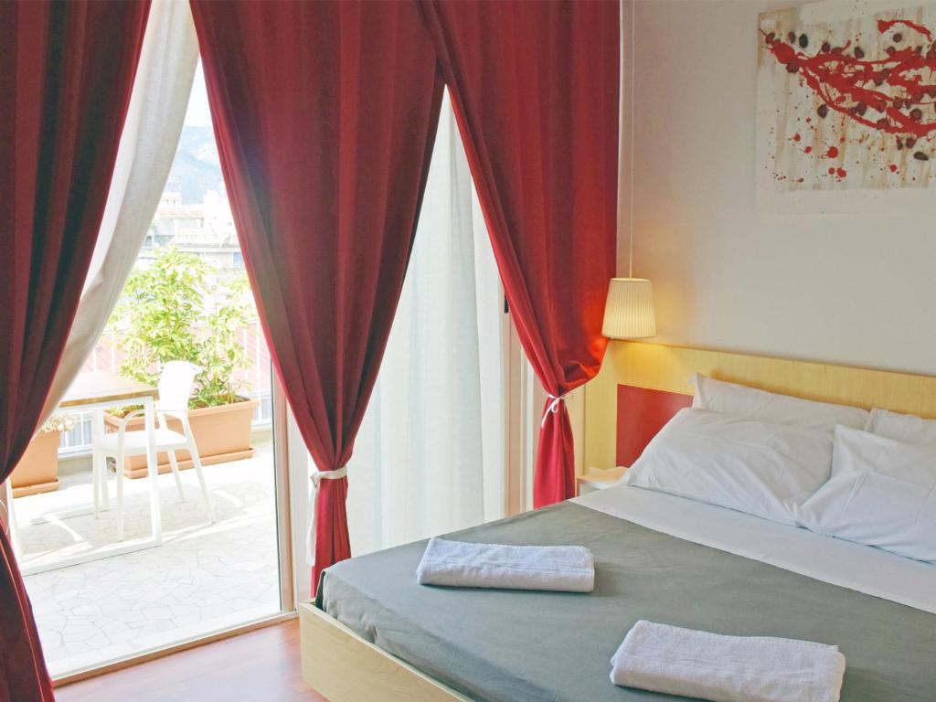 Schlafzimmer mit einem Bett mit roten Vorhängen und einem Fenster in der Unterkunft Bio Hotel Palermo in Palermo