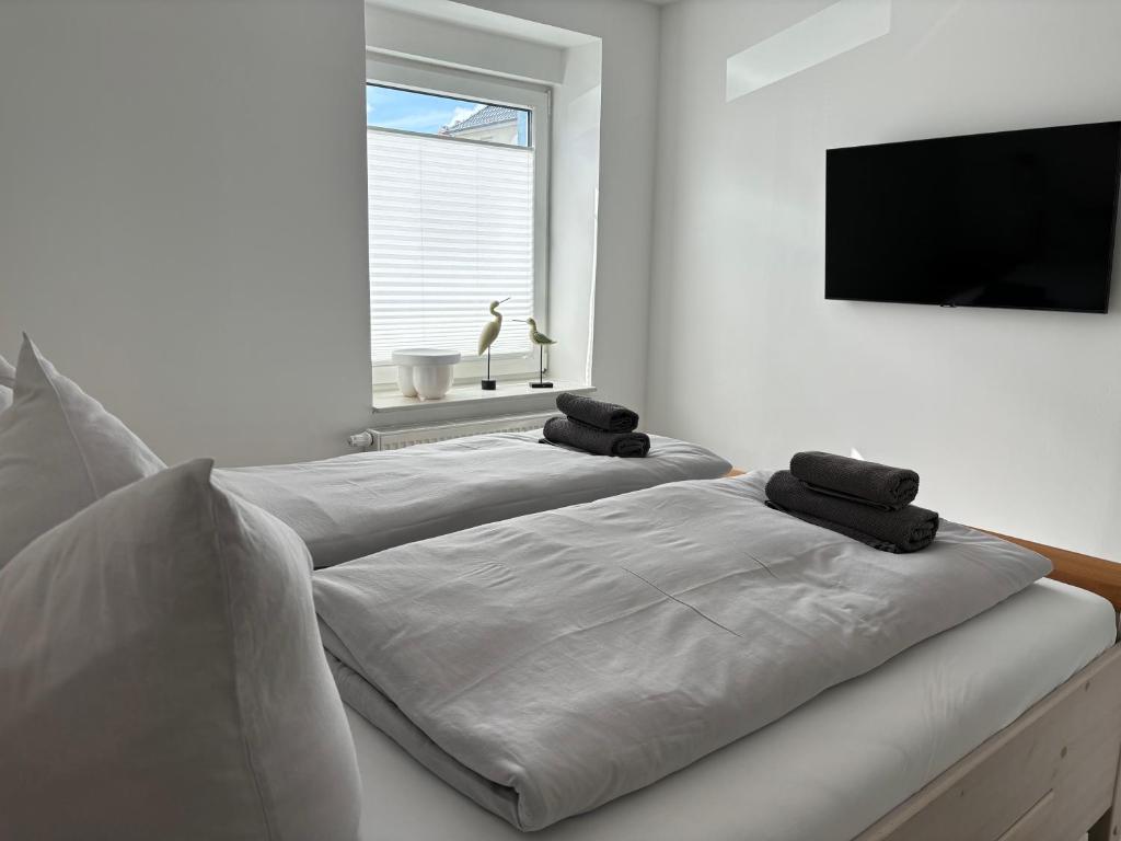 Cette chambre comprend 2 lits blancs et une télévision à écran plat. dans l'établissement Ferienhaus Sachsenblick, à Sassnitz