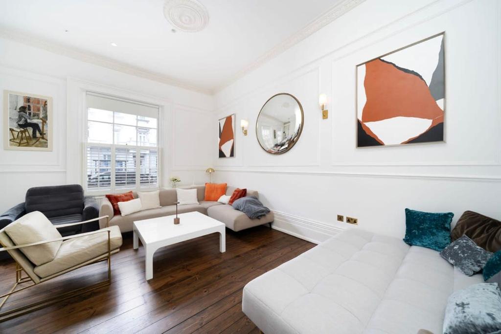 uma sala de estar com um sofá branco e cadeiras em Stylish 2-Bed Flat in London em Londres