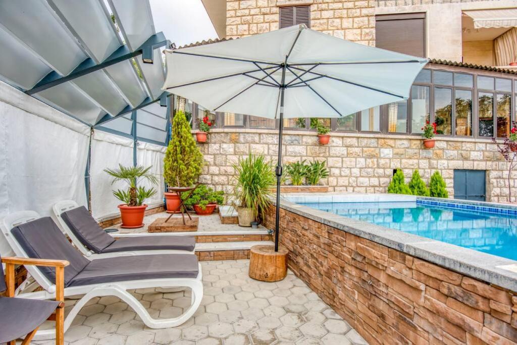 uma piscina com um guarda-sol e cadeiras ao lado de uma piscina em La Kava 1-BR Apt with Terrace in Ain Aar em Al ‘Aţshānah