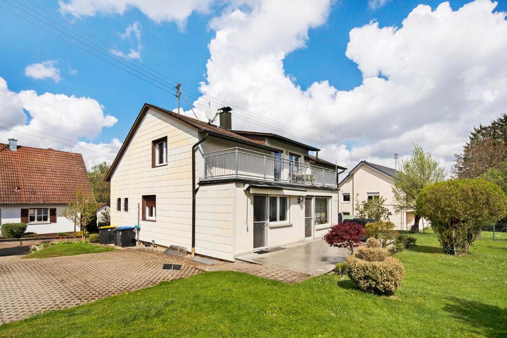 ein weißes Haus mit Balkon darüber in der Unterkunft Ferienwohnung Am Schlehbach in Offingen