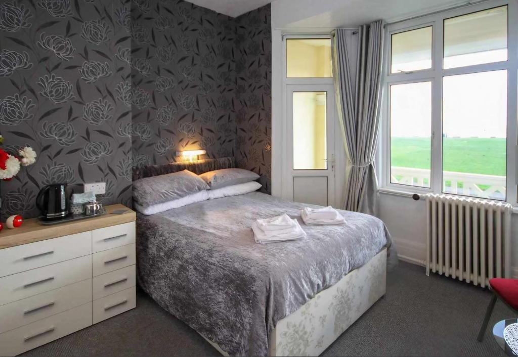 a bedroom with a bed with a dresser and a window at Cambria Hotel in Paignton