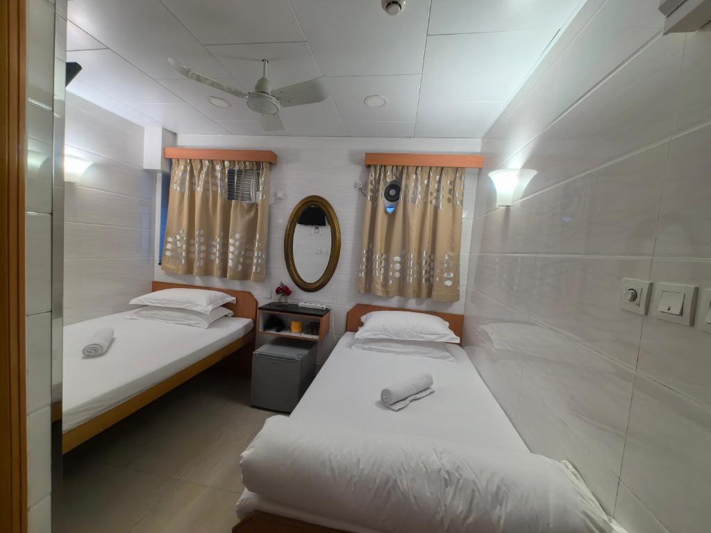 Duas camas num pequeno quarto com um espelho em 香港太阳宾馆 em Hong Kong