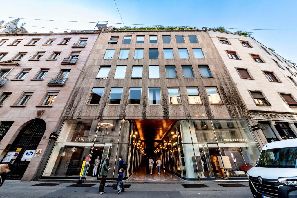 Un palazzo alto con gente che cammina davanti di Dream Suites Milano San Babila a Milano