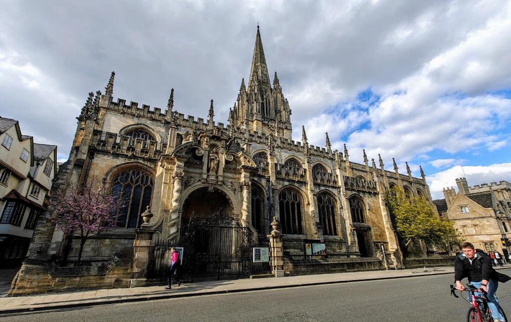 a man riding a bike in front of a cathedral at Headington Haven Homestay in Oxford