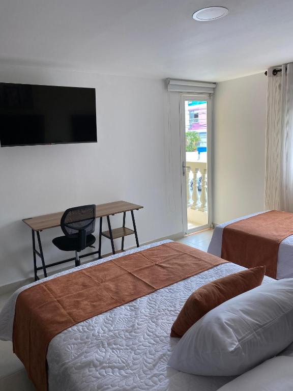 una camera con 2 letti, una scrivania e una TV di Sachar Lodging Apartahotel a Bucaramanga