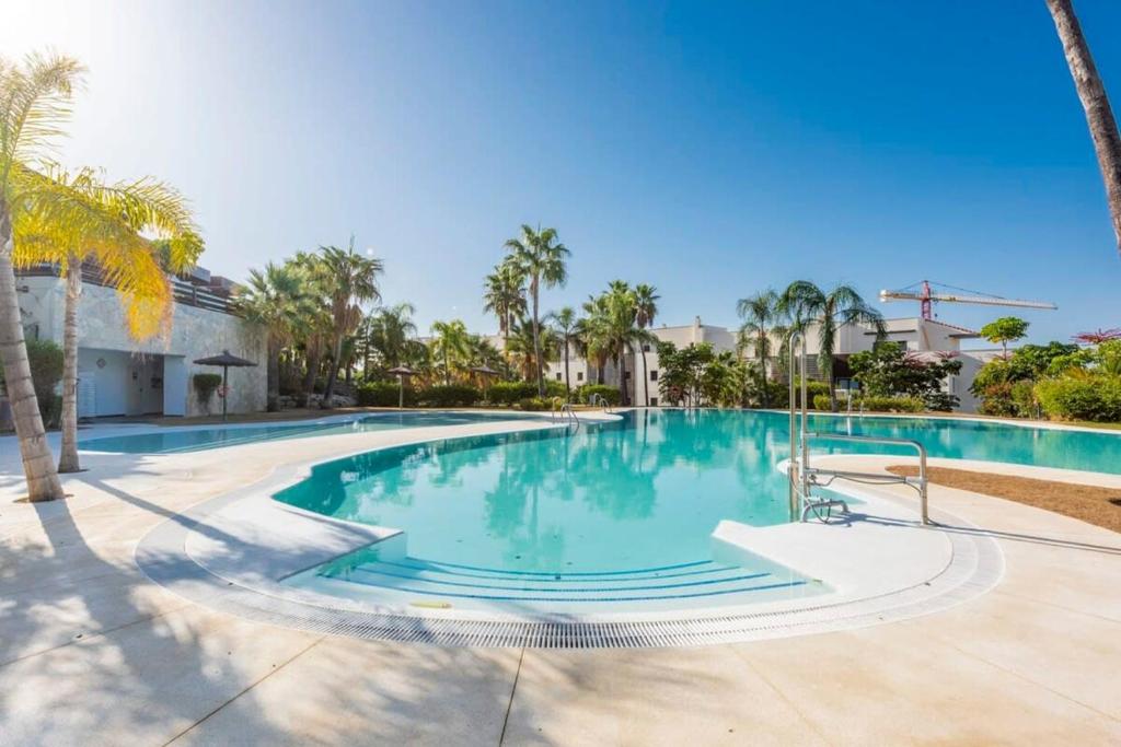 einen Pool mit Palmen in einem Resort in der Unterkunft Resort Marbella Pools Family Golf Wifi Children in Estepona