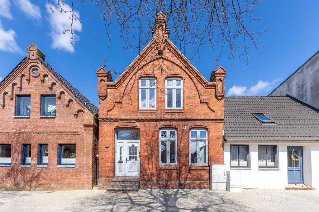 ein altes Backsteingebäude mit einem Turm oben in der Unterkunft Stadthuus 51 in Husum