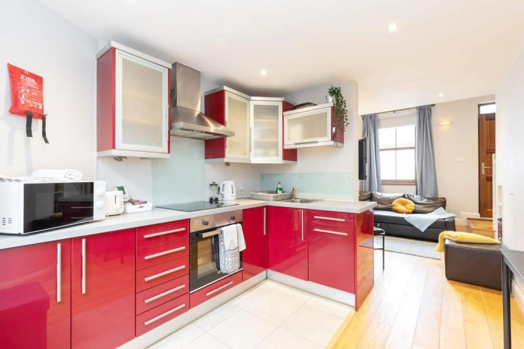 a kitchen with red cabinets and a living room at Central Location 2 BEDROOM 2 BATHROOM FAST WIFI in Dublin